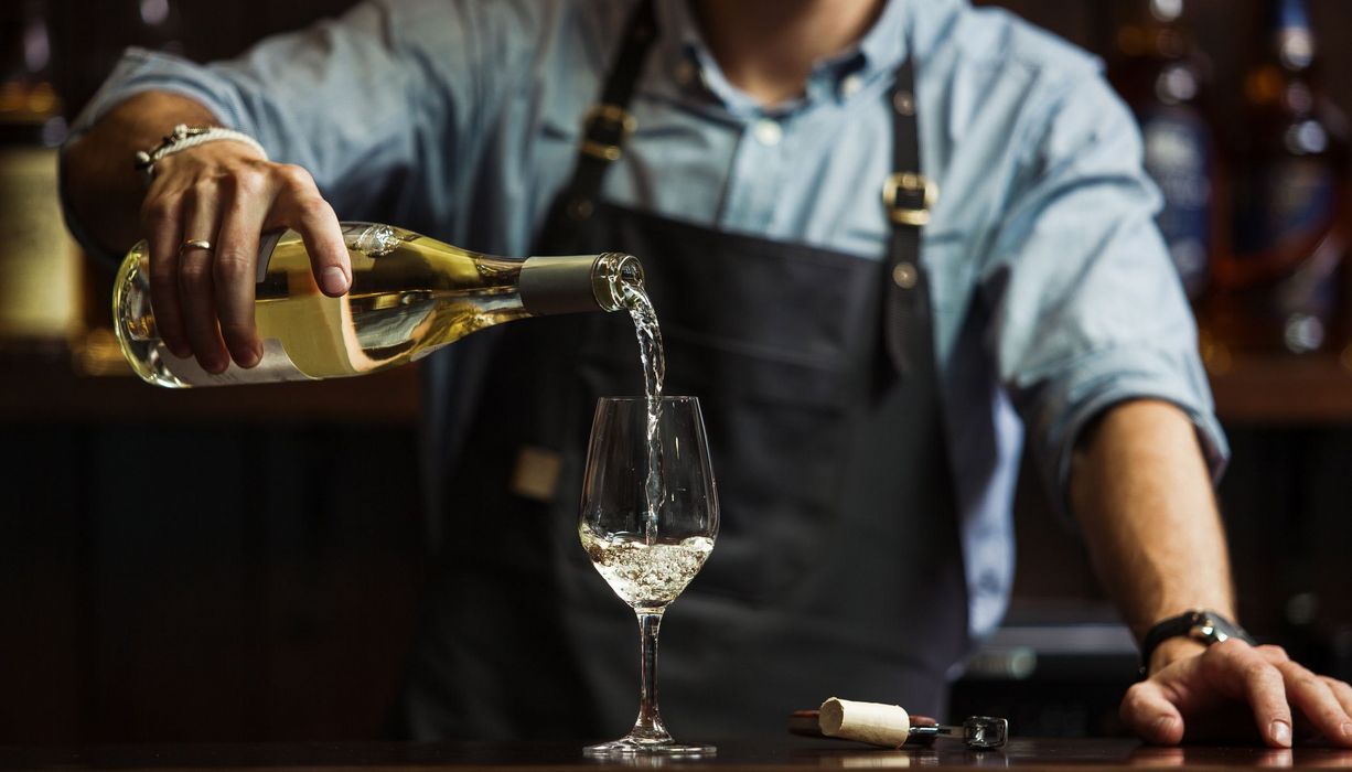 Mann, schenkt ein Glas Wein ein.