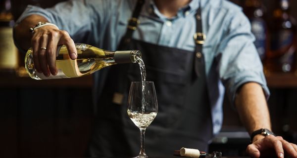 Mann, schenkt ein Glas Wein ein.