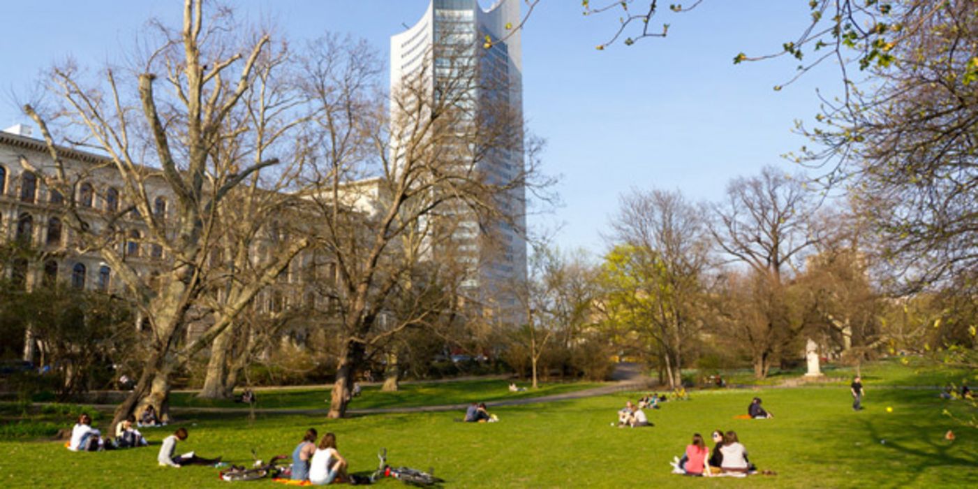 Stadtpark mit Menschen auf der Wiese im Hintergrund ein Hochhaus