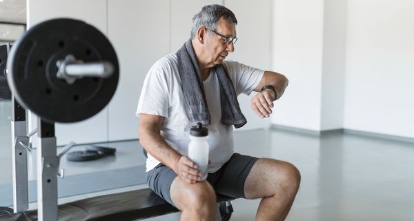 Älterer Mann beim Fitness, schaut auf seine Smartwatch.