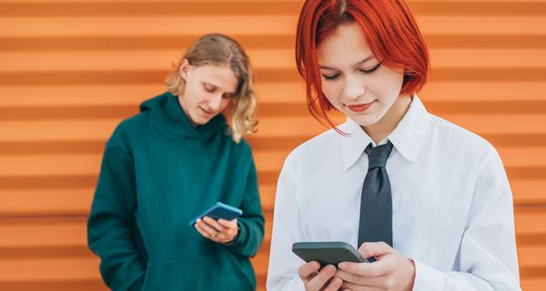 Zwei Jugendliche schauen auf ihr Smartphone.