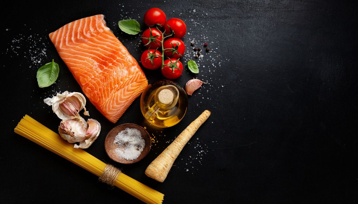 Lachs, Tomaten und Pasta auf einem dunklen Hintergrund.