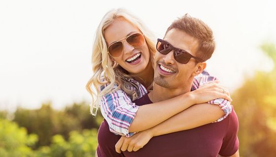 Junges Paar mit Sonnenbrillen umarmt sich.