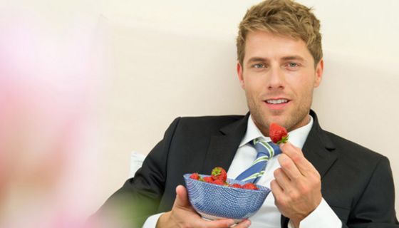 Mann isst Erdbeeren.