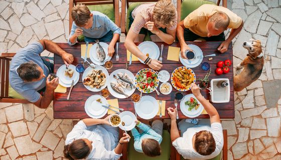 Gruppe von Menschen, die köstliches Essen am festlichen Esstisch mit Salat und gegrilltem Gemüse essen, Blick von oben