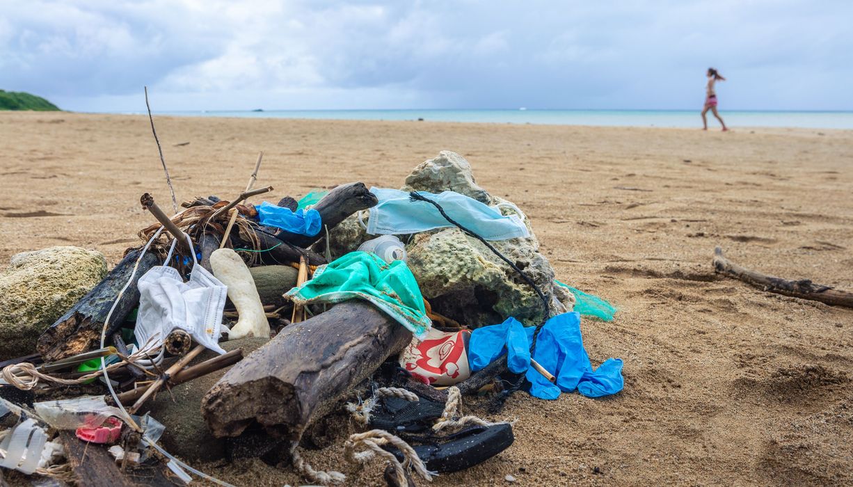 Strand mit Müll, unter anderem Schutzmasken.