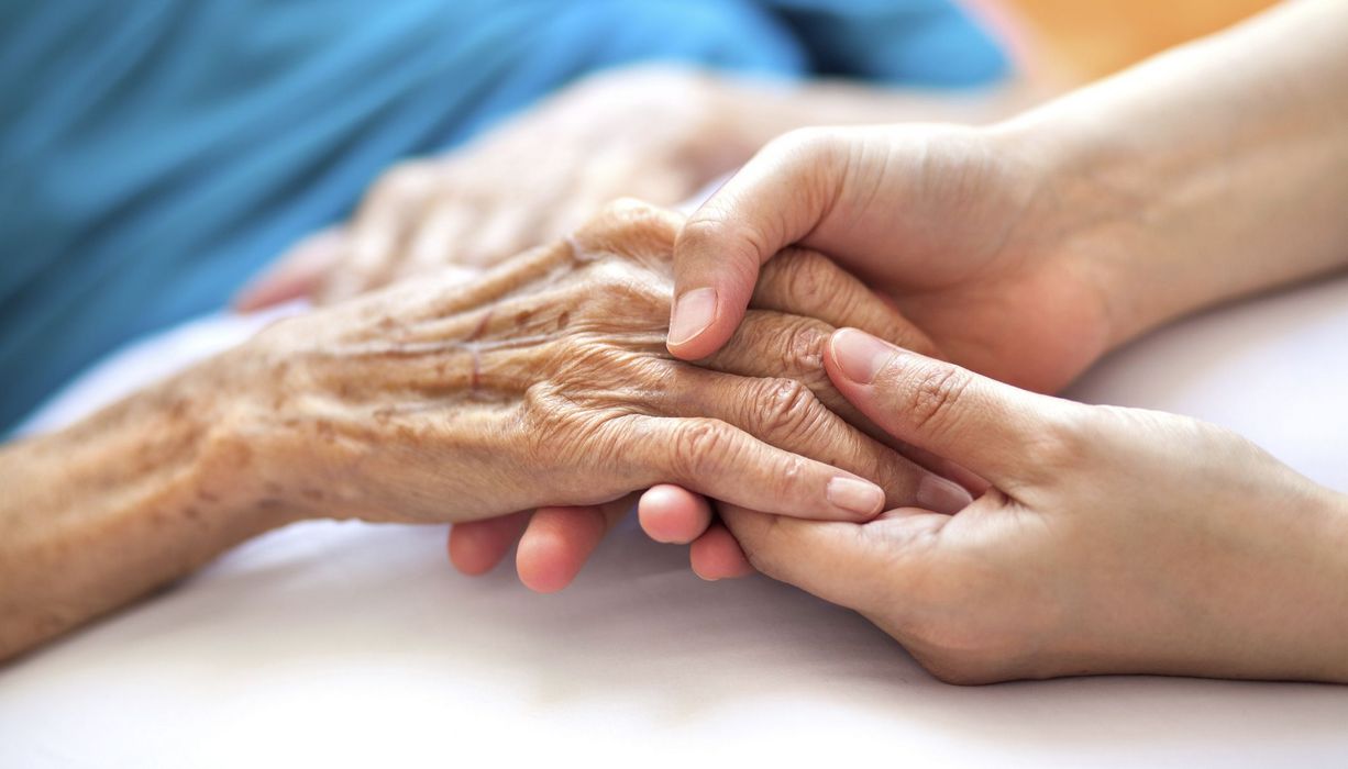 Junge Frau, hält die Hand einer alten Frau.