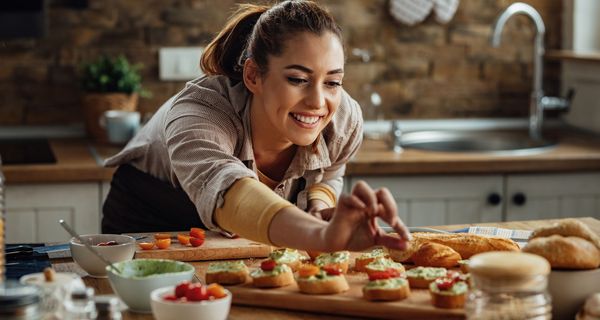 Junge Frau, bereitet Baguettes mit Aufstrich vor.