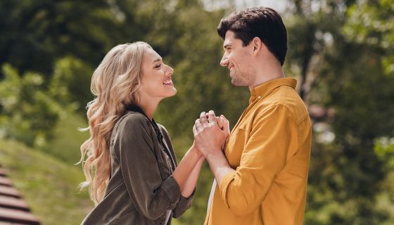 Ein Paar hält sich an den Händen und strahlt sich an.