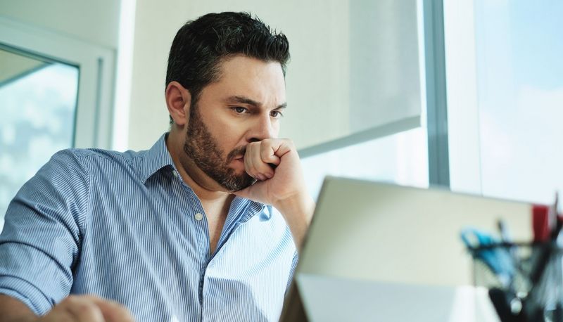 Mann, sitzt vor dem Laptop, Faust geballt.