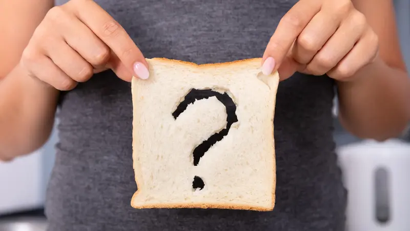 Hände halten eine Scheibe Toast, auf der ein Fragezeichen zu sehen ist.