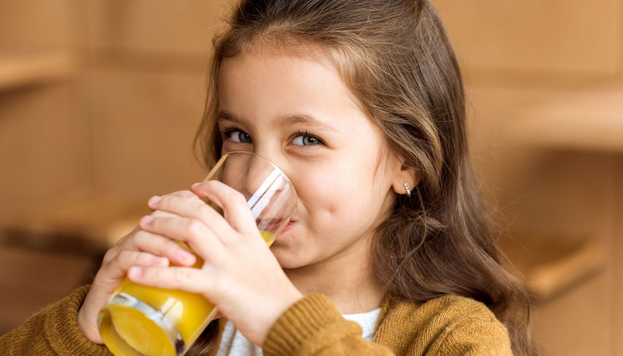 Kind, trinkt ein Glas Orangensaft. 