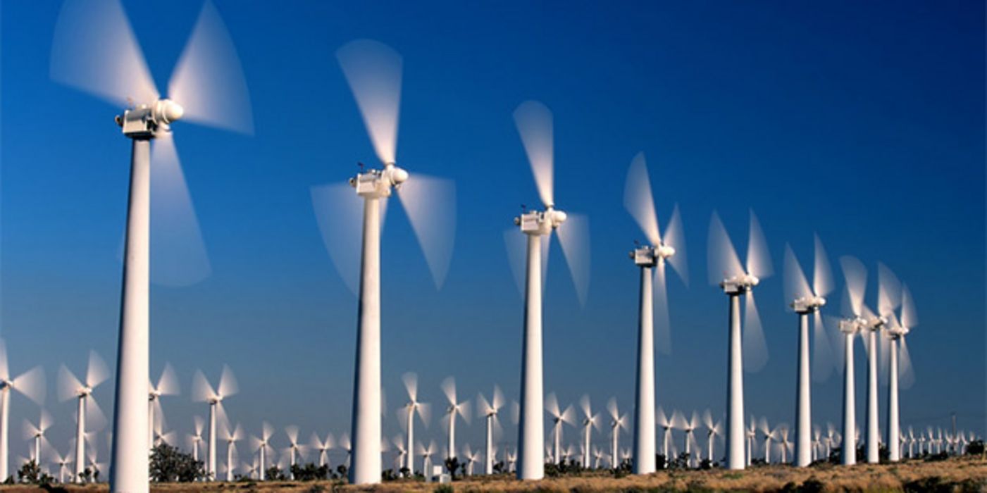 Rotierende Windräder in eine Reihe vor blauem Himmel