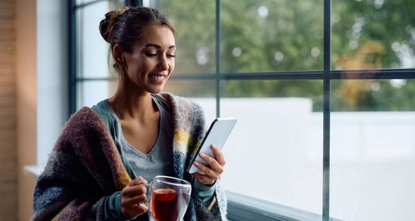 Frau, zu Hause mit Tee und E-Book-Reader.