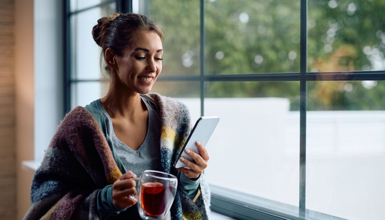 Frau, zu Hause mit Tee und E-Book-Reader.