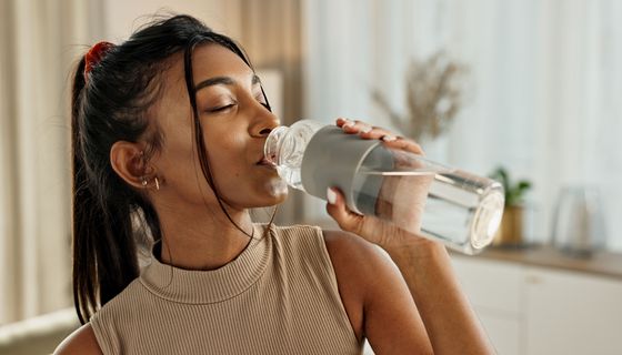 Junge Frau, trinkt Wasser aus einer Flasche.