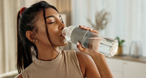 Junge Frau, trinkt Wasser aus einer Flasche.