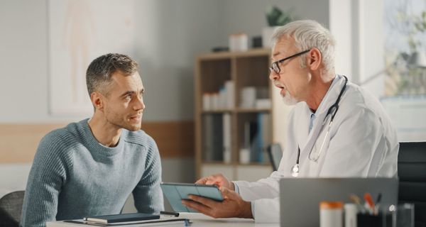 Mann lässt sich vom älterem Arzt beraten.