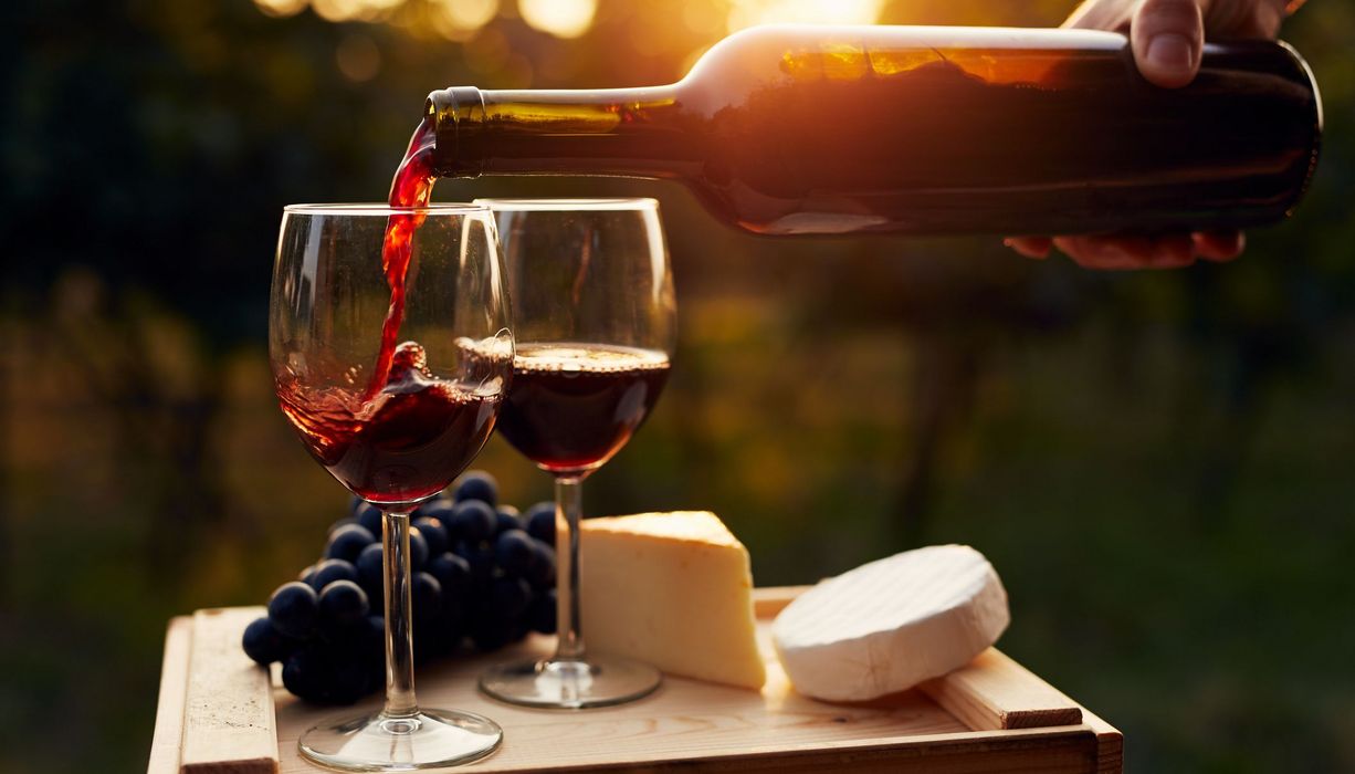 Käse und Wein werden eingeschenkt bei Sonnenuntergang