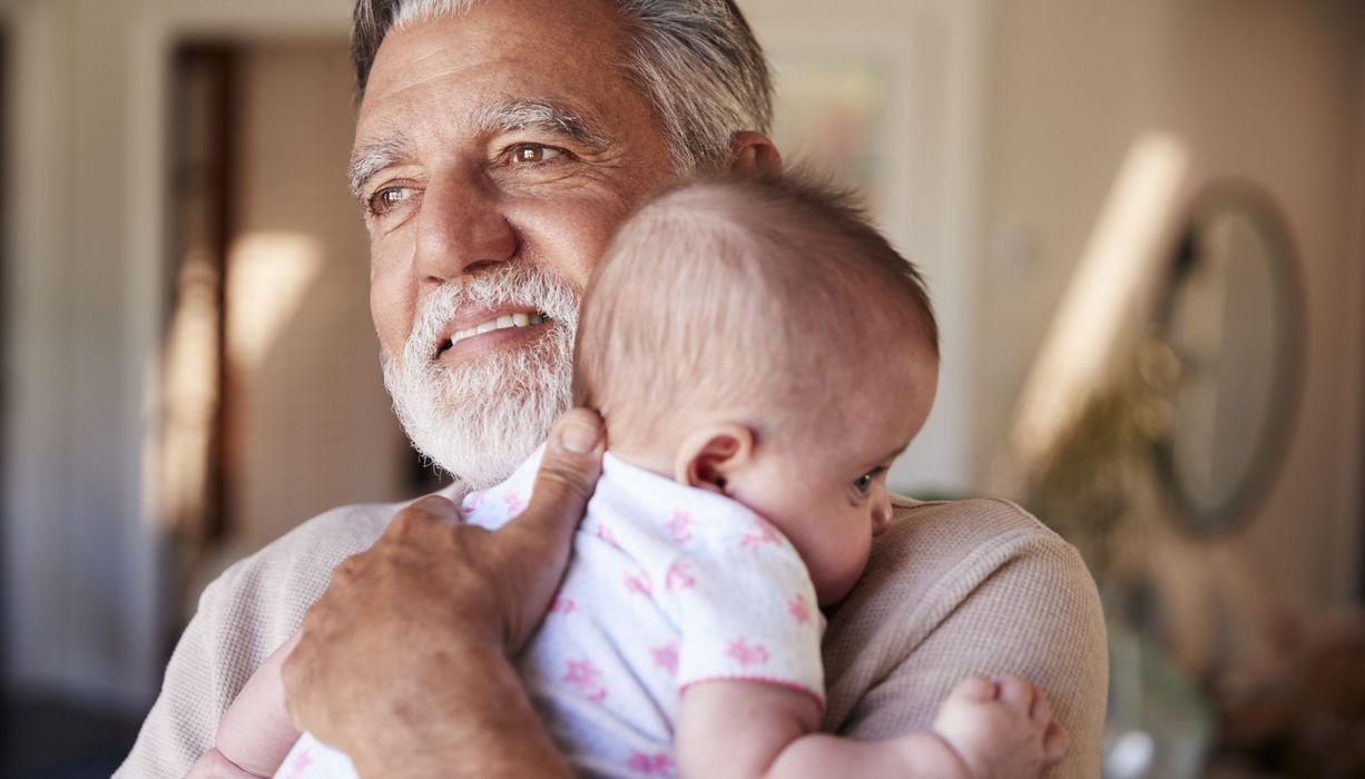 Älterer Vater, hält Baby auf dem Arm.