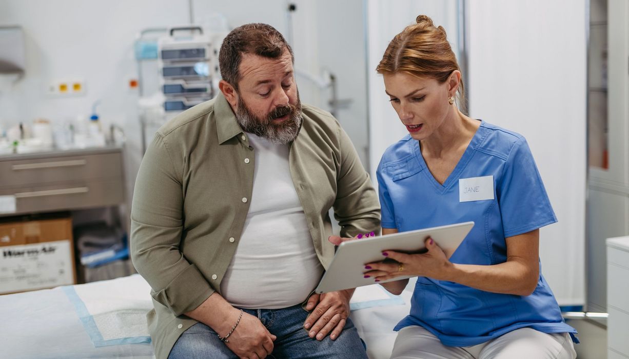 Ärztin erklärt einem Patienten eine Akte.