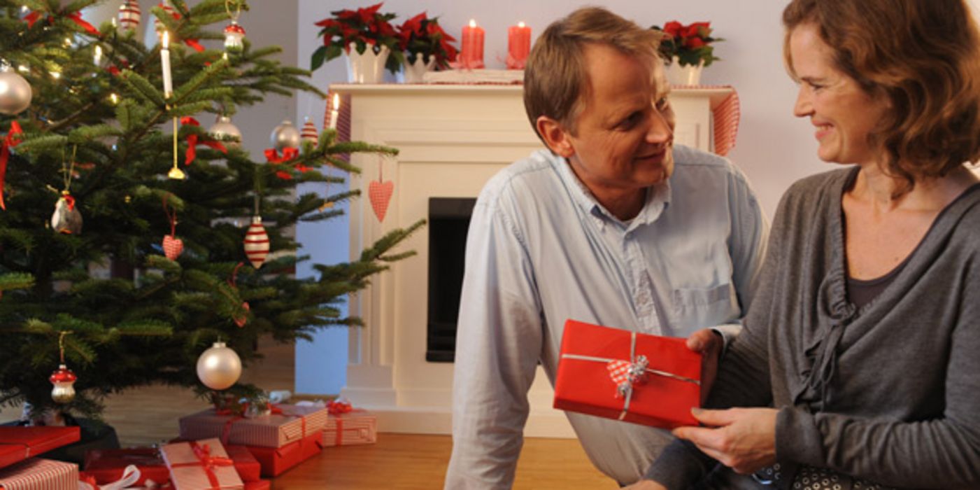 Mann und Frau bei der Bescherung unterm Weihnachtsbaum