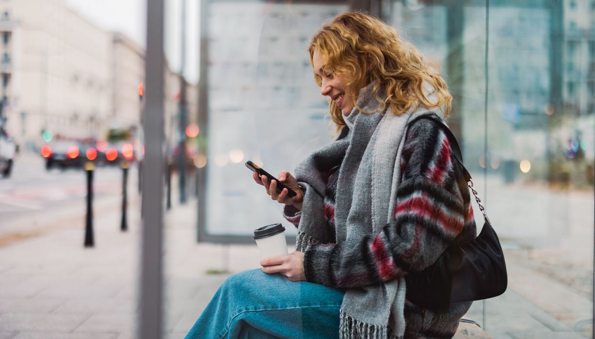 Junge Frau, schaut auf ihr Smartphone.