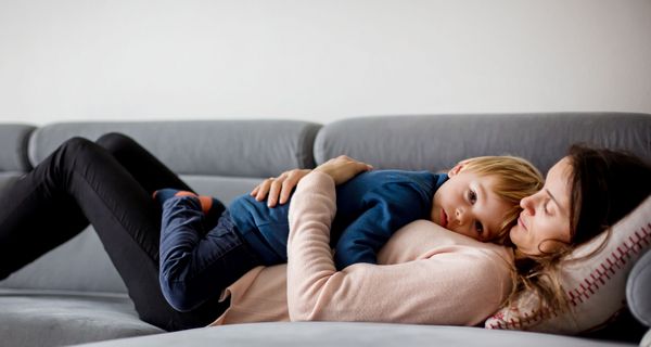 Kleinkind, liegt mit seiner Mutter auf der Couch.