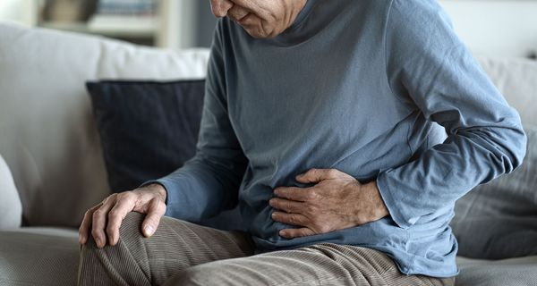 Älterer Mann, fasst sich an den Bauch.