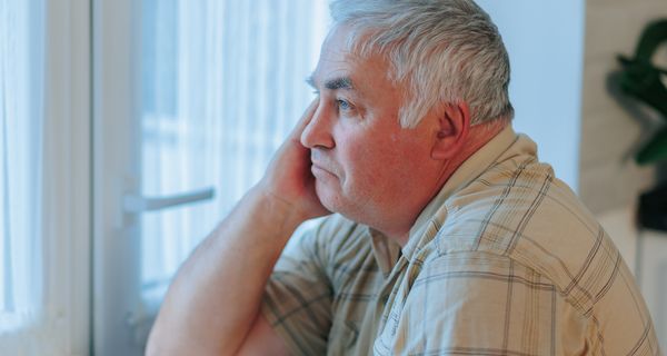 Älterer übergewichtiger Mann, schaut aus dem Fenster.