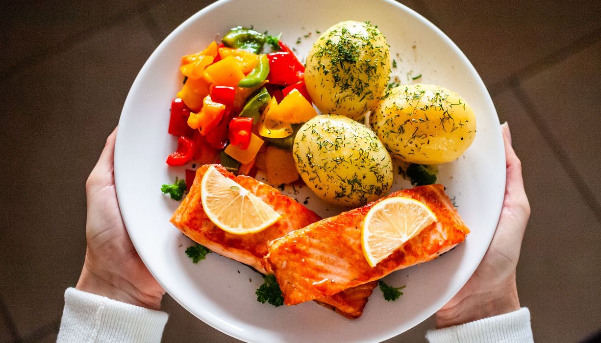 Teller mit Lachs, Kartoffeln und Gemüse.