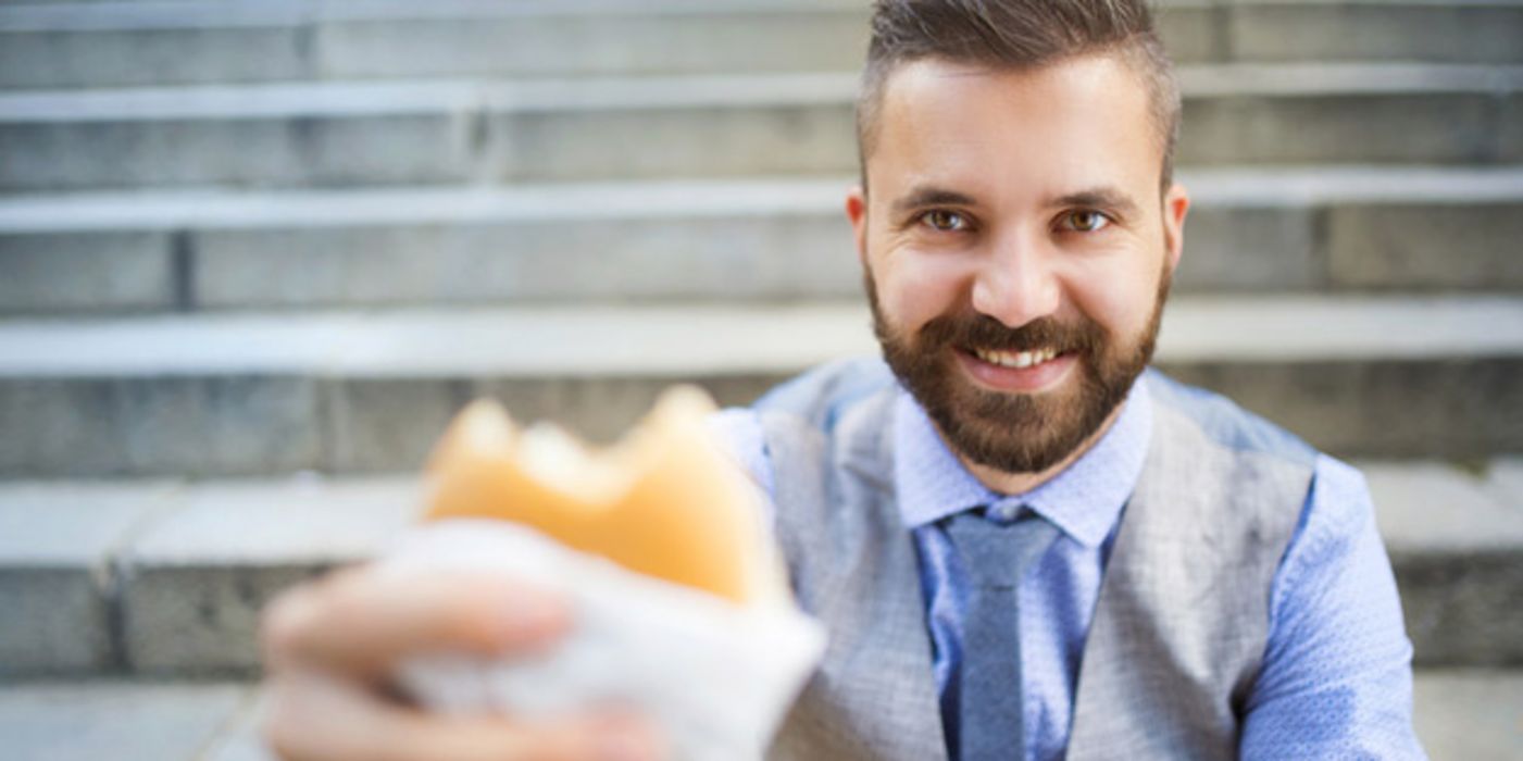 Mann hält Hamburger in der Hand.