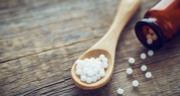 Holzlöffel mit Globuli und brauner Arzneiflasche