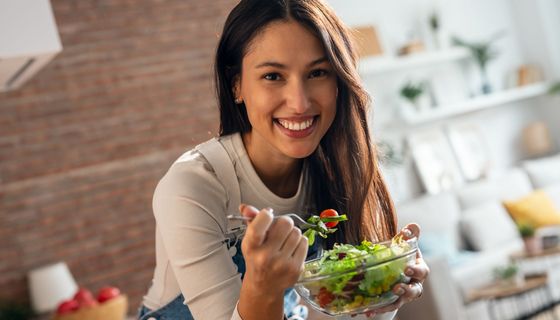 Junge Frau isst einen Salat mit Tomaten und Mais.