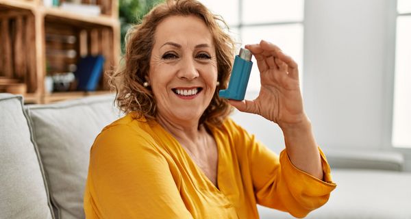 Ältere Frau, hält ein Asthma-Spray in die Kamera.