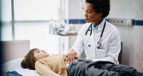 Ärztin, untersucht den Bauch eines Jungen.