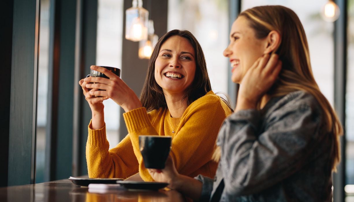 Zwei Freundinnen, trinken Kaffee und sprechen miteinander.