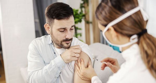 Mann, lässt sich von Apothekerin impfen.