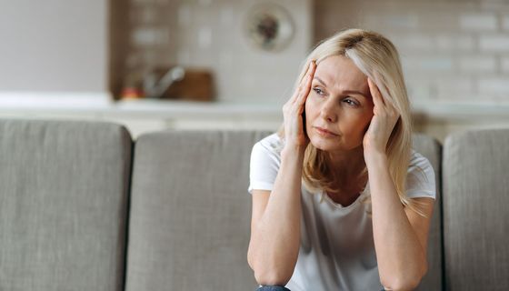Erschöpfte Frau sitzt auf einem Sofa.