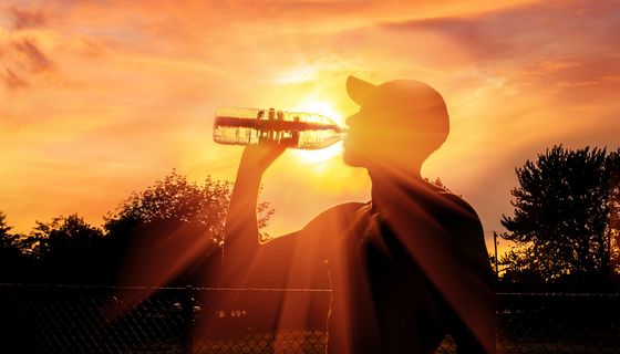 Mann, an einem heißen Sommertag, trinkt Wasser.