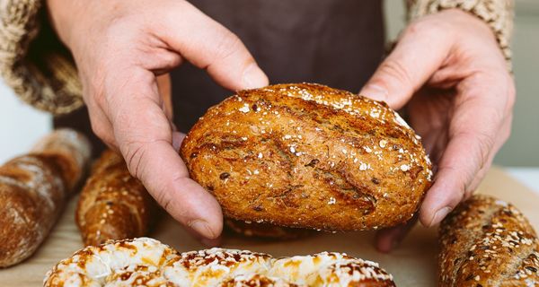 Mann, hält ein Vollkornbrötchen in den Händen.