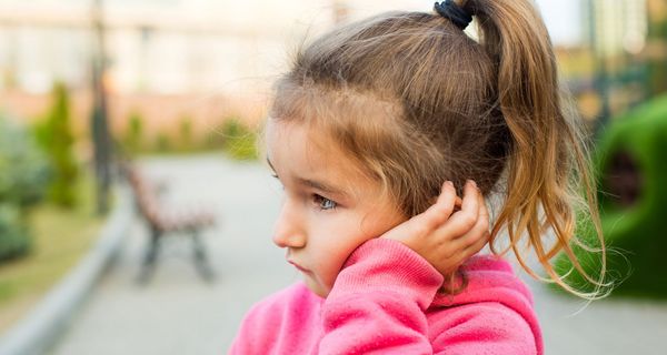 Kind hält sich die Hand ans Ohr.
