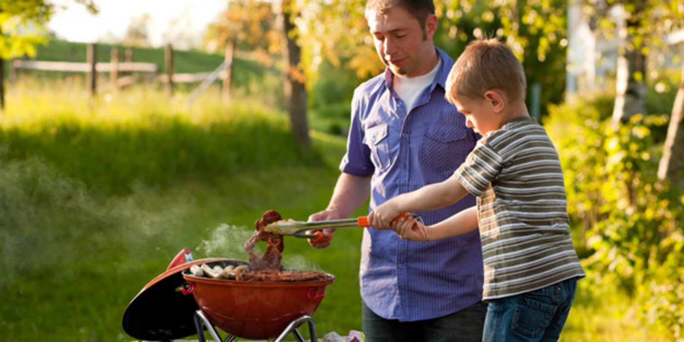 Vater und Sohn grillen Fleisch.