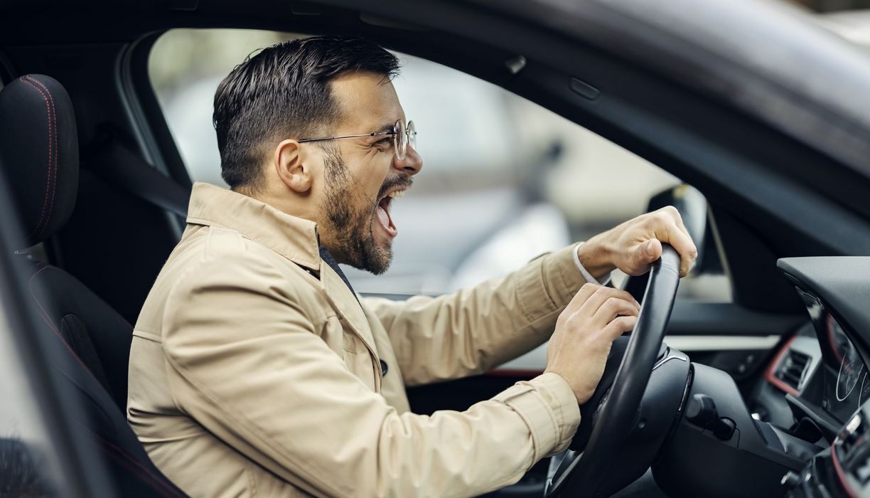 Wütender Autofahrer, schreit hinter dem Lenkrad.