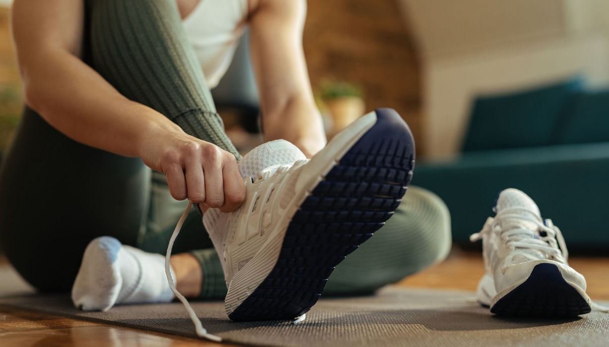 Frau zieht sich Sportschuhe an.