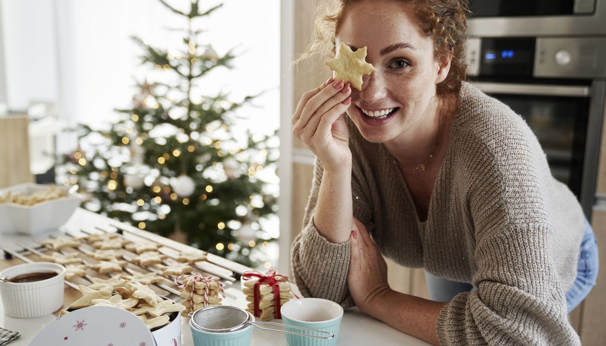 Frau, hält ein Plätzchen in die Kamera.