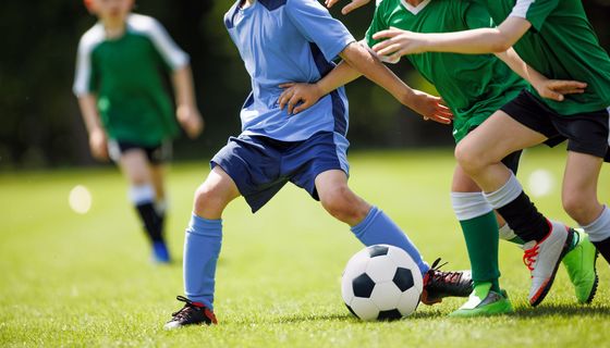Jugendliche kämpfen beim Fußballspielen um den Ball.