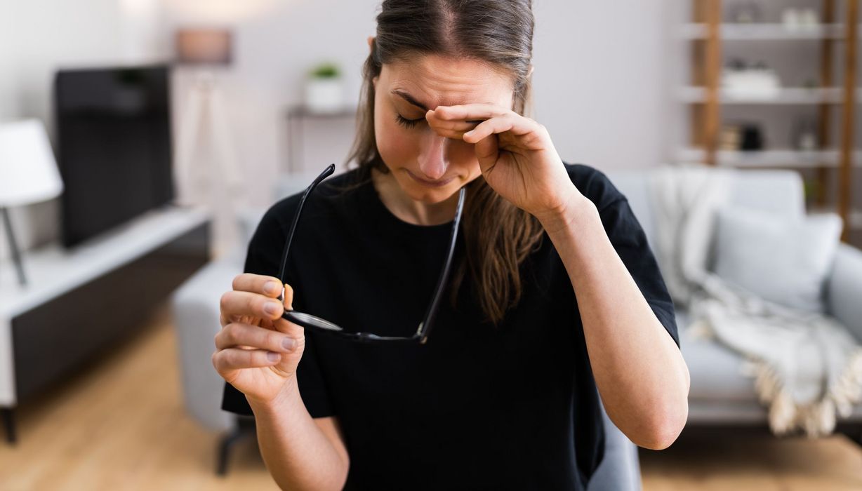 Junge Frau, reibt sich die Augen, ist erschöpft.