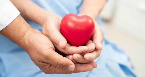 Junge und ältere Hand, halten ein Herz.