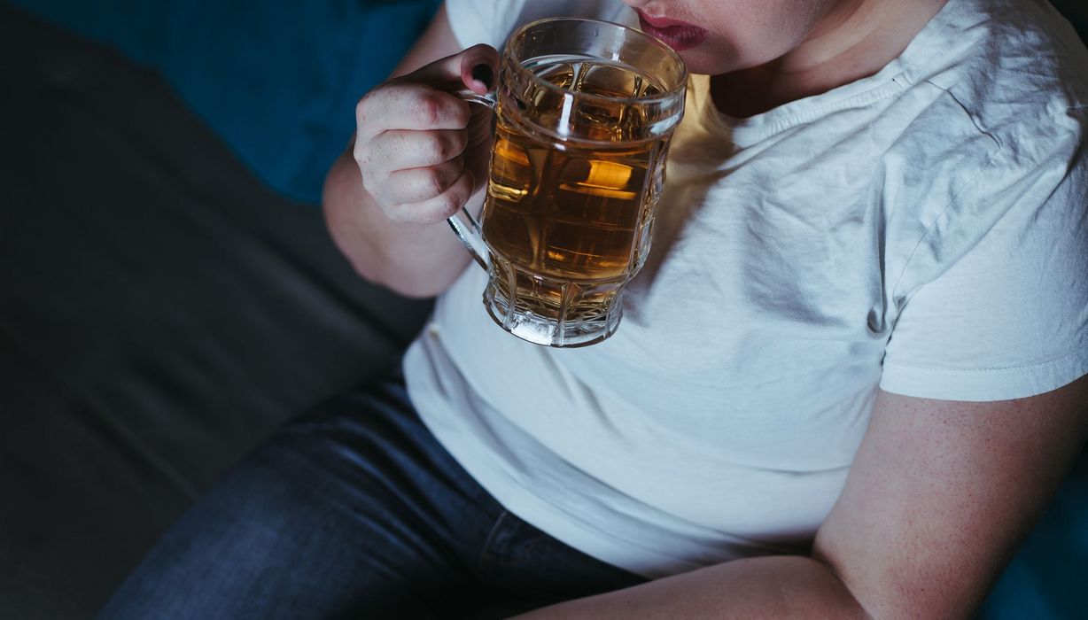 Übergewichtige Frau mit einem großen Glas Bier.